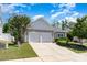 View of the home and driveway featuring mature shade trees, vinyl siding, and an attached garage at 12792 Clydesdale Dr, Midland, NC 28107