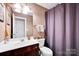 Well-lit bathroom featuring a vanity, toilet, and a shower with a purple curtain at 14940 Carbert Ln, Huntersville, NC 28078