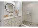 Bright bathroom with a modern vanity, round mirror, and walk-in shower featuring sleek tile design at 17416 Gillican Overlook Rd, Davidson, NC 28036