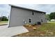 Exterior side view of a gray home with a concrete patio and minimal landscaping at 2012 Crown Point Dr # A, Albemarle, NC 28001