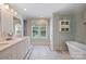 Bright bathroom featuring a freestanding tub, vanity with marble countertop, and decorative window coverings at 2627 Hampton Ave, Charlotte, NC 28207