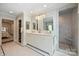 Bright bathroom with dual sinks, marble countertops, walk-in shower, and access to a bedroom and walk-in closet at 2627 Hampton Ave, Charlotte, NC 28207