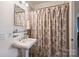 This bathroom features a pedestal sink and shower with patterned curtain at 2627 Hampton Ave, Charlotte, NC 28207
