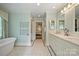 Bright bathroom featuring double vanity, tub, and tiled floors leading to the main bedroom at 2627 Hampton Ave, Charlotte, NC 28207