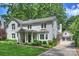 Charming white brick home with lush landscaping and a welcoming front porch with swing at 2627 Hampton Ave, Charlotte, NC 28207