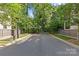 Wide view of the street showing a basketball hoop, mature trees and green landscape at 2906 Hillside Springs Dr, Charlotte, NC 28209