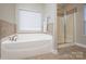 Bright bathroom showcasing soaking tub with tile surround and glass enclosed shower at 3664 Privette Rd, Matthews, NC 28104