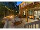 Backyard with a stone patio, built-in fire pit, picnic table, and hot tub under the deck, enhanced by string lights at 3817 Arial Ln # 145, York, SC 29745