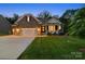 Charming brick home boasts a manicured lawn, a two-car garage, and a welcoming front porch with lights on at dusk at 3817 Arial Ln # 145, York, SC 29745
