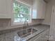 A close-up view of the kitchen sink with granite countertops and bright natural light at 406 4Th St, Spencer, NC 28159