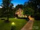 Beautiful brick house with a well-maintained lawn, illuminated by landscape lighting at dusk at 4339 Shannamara Dr, Matthews, NC 28104