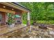 Covered stone patio with outdoor fireplace and fire pit overlooking a leafy backyard at 4339 Shannamara Dr, Matthews, NC 28104