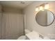 This bathroom has a shower/tub combination, commode, vanity, framed circular mirror and modern lighting at 4938 Sunset Ridge Ct, Charlotte, NC 28269