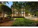 Exterior shot of the building with lush lawn, landscaping and white picket fence illuminated in the evening at 5009 Sharon Rd # E, Charlotte, NC 28210