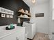 Laundry room with black accent wall, white cabinets, shelving, and new washer at 5013 Hamilton Mill Dr, Waxhaw, NC 28173