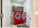 Functional laundry room boasts vibrant red washer and dryer set with convenient overhead storage at 5025 Kinross Ln, Indian Land, SC 29707