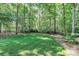 Well-maintained backyard featuring green grass, mature trees, and a wood fence at 516 Aspen Ln, Indian Trail, NC 28079