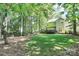 Lush backyard featuring green grass, mature trees, and a home with back deck at 516 Aspen Ln, Indian Trail, NC 28079