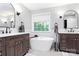 Bright bathroom with double vanities, a soaking tub below the window, and neutral finishes at 516 Aspen Ln, Indian Trail, NC 28079