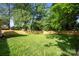 A backyard with a wooden fence, lush green grass, and large trees at 6100 Ashcrest Dr, Charlotte, NC 28217