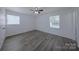 Bedroom with hardwood floors, ceiling fan, and two bright windows for natural light at 6124 Coach Hill Ln, Charlotte, NC 28212