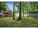 Spacious backyard with mature trees and a covered patio with stone outdoor kitchen at 6640 Autumn Gate Ln, Charlotte, NC 28216
