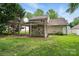 A lush backyard featuring a covered patio with an outdoor stone kitchen and mature trees at 6640 Autumn Gate Ln, Charlotte, NC 28216