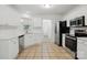 Kitchen with stainless steel appliances, white cabinets and tile floors, with a view into the half bathroom at 6640 Autumn Gate Ln, Charlotte, NC 28216