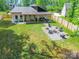 Aerial view of a backyard with a fire pit, chairs, stump tables, lush green grass, and modern house at 7728 Shalom Dr, Charlotte, NC 28216