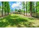 Large backyard with a fire pit, wooden fence, mature trees, and a modern house featuring a metal roof at 7728 Shalom Dr, Charlotte, NC 28216