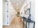 Long hallway with wood-look flooring, white walls, and a decorative table with accessories at 7728 Shalom Dr, Charlotte, NC 28216
