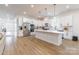 Bright, open kitchen features white cabinets, stainless steel appliances, a spacious island, and wood flooring at 7728 Shalom Dr, Charlotte, NC 28216