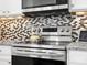 Stainless steel oven and cooktop with stylish mosaic tile backsplash at 8037 Lynwood Sq, Waxhaw, NC 28173
