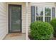 Close-up of the front door and window with black shutters, complemented by manicured shrubbery at 908 Dairy Meadow Ct, Monroe, NC 28110
