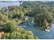 Aerial view showcases the house with waterfront and dock, all surrounded by a canopy of lush trees at 108 Balmoral Dr, Mooresville, NC 28117