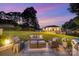 Picturesque backyard featuring outdoor seating, built-in grill, and gazebo overlooking the lake at dusk at 108 Balmoral Dr, Mooresville, NC 28117