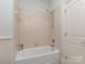 Bright bathroom features a tiled tub and shower with updated fixtures and a neutral color scheme at 10924 Lederer Ave, Charlotte, NC 28277