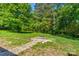 A backyard featuring a stone fire pit, tiki torches, and a beautiful, green wooded perimeter at 11861 Nc Hwy 73 E Hwy, Mount Pleasant, NC 28124