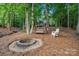 Secluded backyard with a fire pit, swing, chair, bridge and lush trees; ideal for outdoor relaxation at 131 Sierra Woods Dr, Troutman, NC 28166