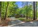 Scenic driveway leading to a well-maintained brick home with a carport, surrounded by lush greenery and trees at 131 Sierra Woods Dr, Troutman, NC 28166