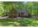 Charming brick home featuring a lush, landscaped front yard and inviting entrance, nestled amongst mature trees at 131 Sierra Woods Dr, Troutman, NC 28166