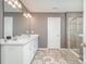 A main bathroom featuring double sinks with white cabinets, tiled floor, and glass-enclosed shower at 15131 Oleander Dr, Charlotte, NC 28278