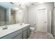 Bright bathroom featuring double sinks, gray cabinets, and a separate shower and toilet area at 17307 Villanova Rd, Huntersville, NC 28078