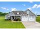 Beautiful home exterior with manicured lawn, gray siding, stone accents, and a three-car garage at 210 Dorothy Dr, China Grove, NC 28023