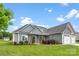 Charming home exterior featuring gray siding, stone accents, well-manicured lawn, and a three car garage at 210 Dorothy Dr, China Grove, NC 28023