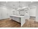 A modern kitchen featuring a large island with sink, white cabinets, stainless steel appliances, and hardwood floors at 2710 Briarcliff Pl, Charlotte, NC 28207