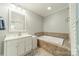 Bright bathroom with a soaking tub, white vanity, and neutral tile at 2915 Wesley Ave, Charlotte, NC 28205