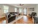 Open living room with hardwood floors, ceiling fan, grey sectional, and view of the front door at 2915 Wesley Ave, Charlotte, NC 28205