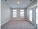 Bright bedroom featuring neutral walls, plush carpet, two windows, and access to an outdoor balcony or patio at 3069 Founding Fathers Dr, Gastonia, NC 28056