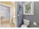Powder room featuring neutral tile flooring, soft gray paint, and a window with views of the trees outside at 3932 Rounding Run Rd, Charlotte, NC 28277